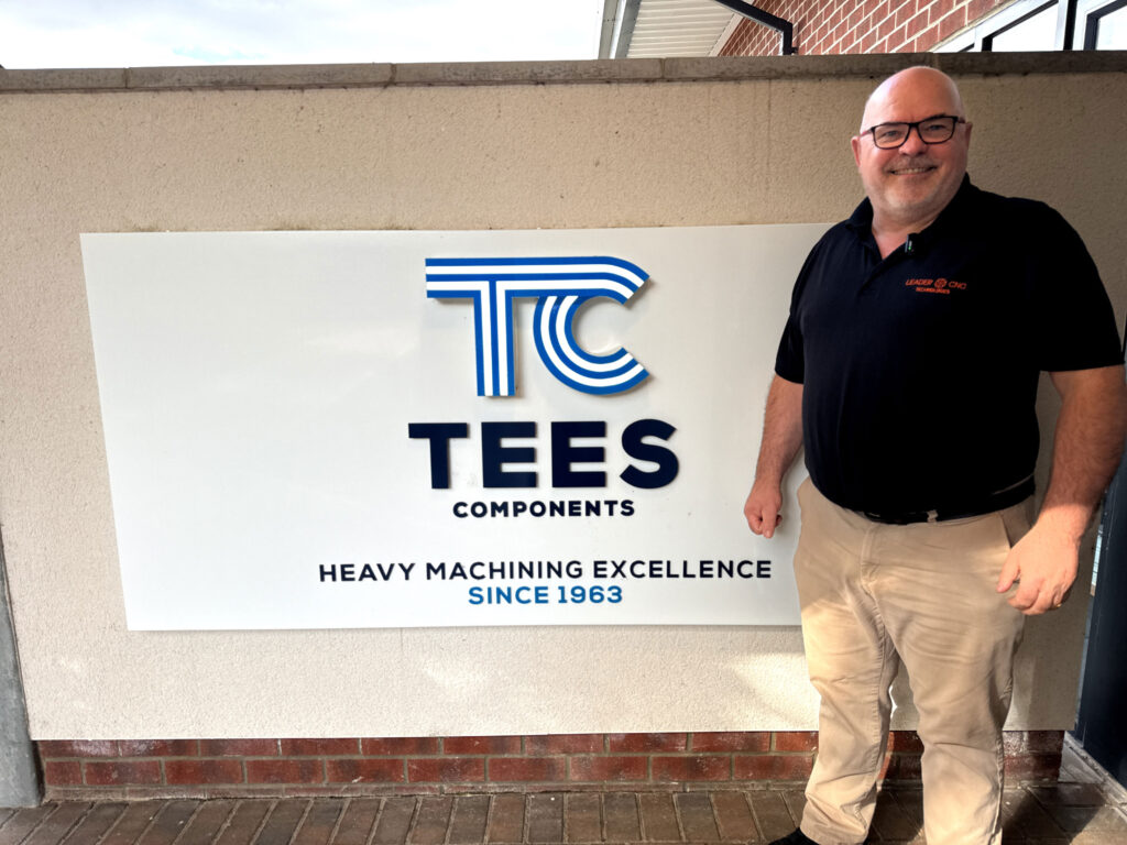 Leader CNC Technologies team member standing outside Tees Components welcome sign